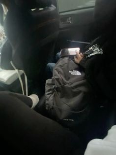 a person sitting in the back seat of a car with a backpack on their lap