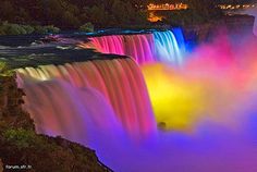 the waterfall is lit up with colored lights and water flowing down it's sides