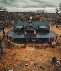 an aerial view of a house in the middle of trees and dirt area with cloudy skies