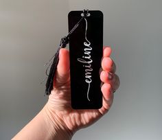 a person holding up a black tag with the word love written on it in white ink