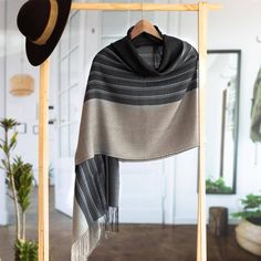 a black and white striped shawl hanging on a wooden hanger in a room