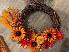 an autumn wreath with sunflowers and corn on the floor next to a book