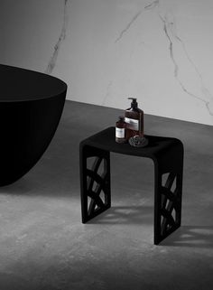 a black table with soap and lotion on it next to a bathtub in a bathroom