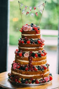 a three tiered cake with berries and flowers on top is displayed for the camera