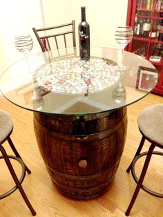 a wine barrel table with three stools around it and a bottle on the top