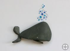 a metal sculpture of a whale with blue beads on it's tail is shown against a white background