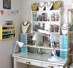 a craft room with lots of crafting supplies on the desk and shelves above it