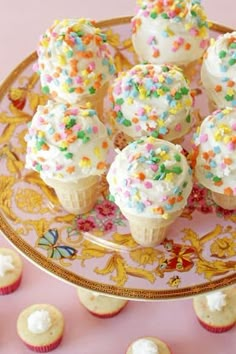 small cupcakes with sprinkles on a gold plate next to other cupcakes