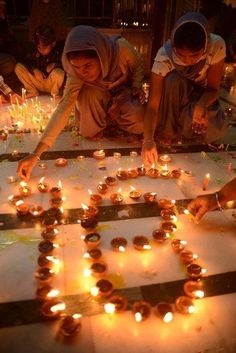 two people lighting candles in the shape of a heart