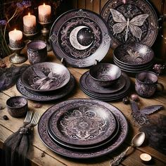 a table topped with lots of black plates covered in purple designs and candles on top of it