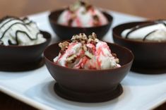 four desserts are arranged in small bowls on a plate