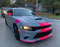 a gray car with pink stripes parked on the street