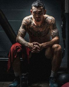 a man with tattoos sitting on the ground