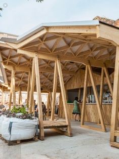 a wooden structure sitting on top of a cement ground next to a building filled with people