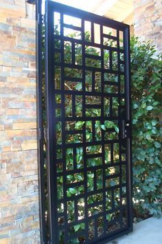 an iron gate in front of a brick wall with plants growing on the outside and inside