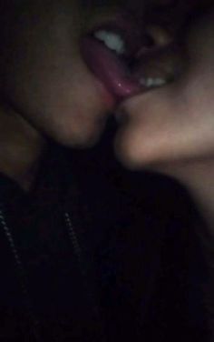 two people are kissing in the dark with their faces close together