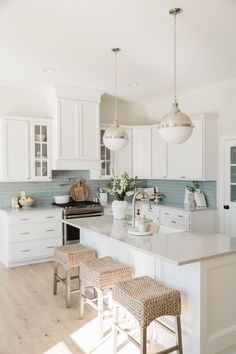 a kitchen with white cabinets and an island in the middle, two stools on each side