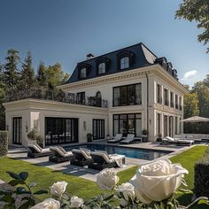 a large white house with a pool in the front yard and lawn furniture around it