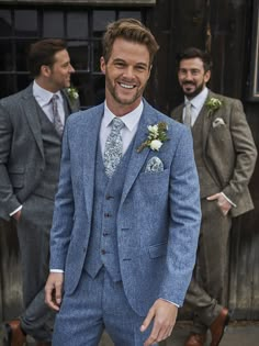 two men in suits standing next to each other and one is wearing a flowered boutonniere