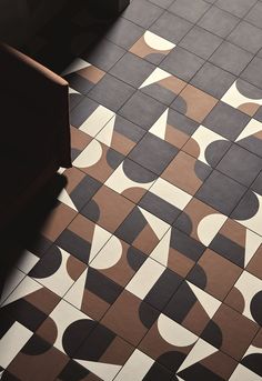 a tiled floor with black and white designs on it's sides, next to a chair