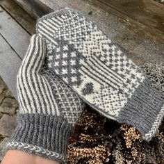 a person's hand wearing knitted mitts on a wooden bench