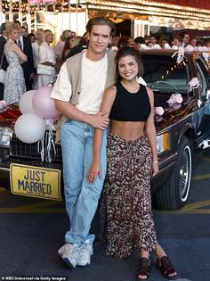 a man and woman standing in front of a car