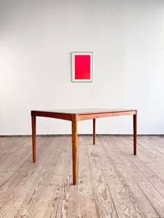 a wooden table sitting on top of a hard wood floor next to a white wall