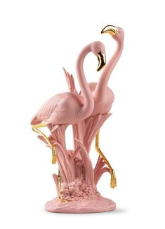 two pink flamingos standing next to each other on top of a white surface with gold accents