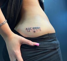 a woman's stomach with arabic writing on the side and pink nail polishes