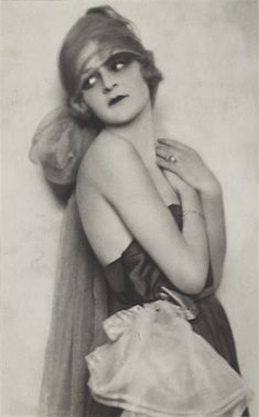 an old black and white photo of a woman with her arms around her neck, wearing a dress