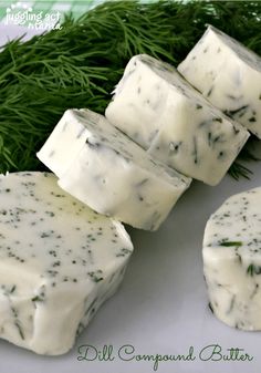 four pieces of cheese sitting on top of a white plate next to some green herbs