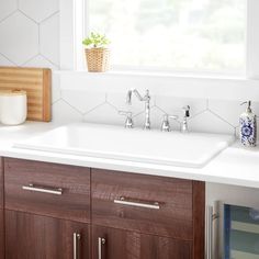 a white sink sitting under a window next to a wooden cabinet and counter top in a kitchen