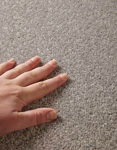 a person's hand on top of a gray carpet