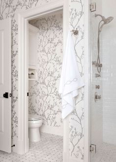 an open door leading to a bathroom with wallpaper on the walls and a toilet