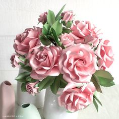 pink flowers are in white vases on a table