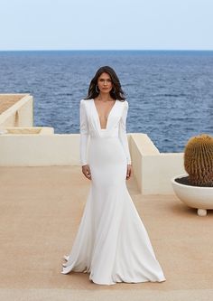 a woman in a white wedding dress standing next to a cactus