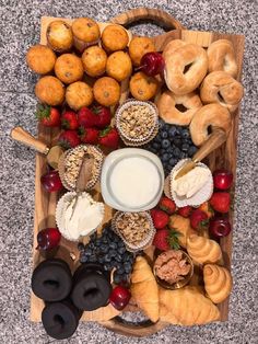 an assortment of pastries and fruit on a wooden platter with a bowl of yogurt