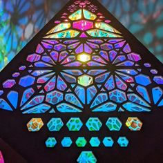 a colorful stained glass window in the shape of a triangle with diamond shapes on it