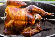 a roasting chicken is being cooked on an outdoor bbq grill with tongs