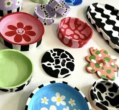 many different colored plates and bowls on a table with flowers painted on the lids,