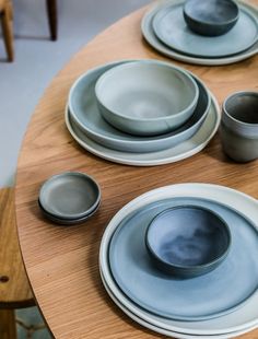 a wooden table topped with plates and bowls