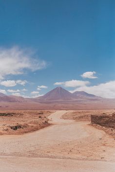 a dirt road in the middle of nowhere with mountains in the backgrouund