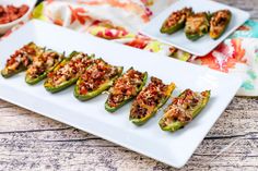 stuffed bell peppers on a white platter with other dishes in the backgroud