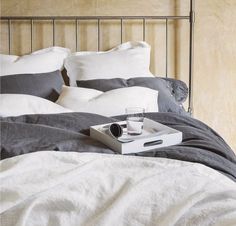 a tray with an empty glass on top of a bed next to pillows and blankets