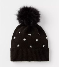 a black beanie with white stars and a pom - pom on top