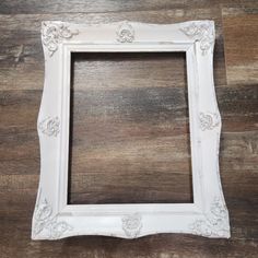 an old white frame sitting on top of a wooden floor in front of a wall