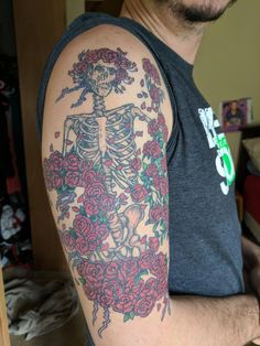 a man with a skeleton and roses tattoo on his arm