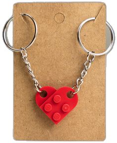 a red heart shaped keychain with two small buttons attached to the front of it