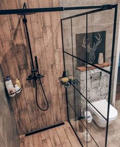 a bathroom with a shower, toilet and wooden flooring is shown in this image