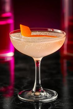 an orange garnish sits on the rim of a glass filled with a drink